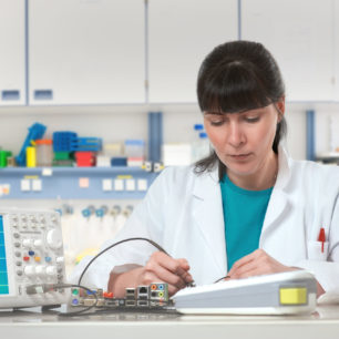 Ingeniero o técnico femenino joven repara equipos electrónicos en instalaciones de investigación. DOF bajo, foco en las pestañas. Esta imagen está tonificada.